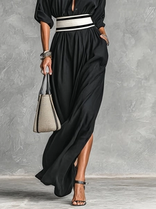 Detailed view of black dress with a wide striped waist belt and high side slit