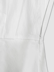Detailed view of invisible zipper and elegant pleats on white professional dress
