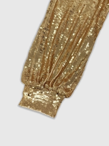 Close-up of golden sequined lantern sleeve with elastic cuff and premium metallic finish