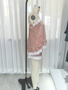 Detail of dusty pink two-piece set with white lace trim and fringe on linen-style fabric