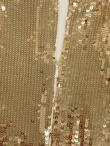 Close-up of golden sequin embroidery with a discreet white invisible zipper detail