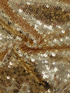 Macro shot of shimmering golden sequin fabric showing reflective metallic texture and folds