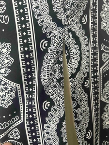 Detail of floral paisley print and lace borders on black and white slit trousers