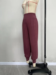 Detail of high-waist elastic band and soft pleated fabric on bordeaux yoga pants