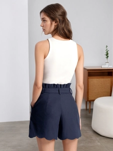 Chic high-waisted scalloped navy shorts paired with a white sleeveless knit tank top