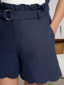 Detail of high waisted navy paperbag shorts with D-ring belt and scalloped hemline