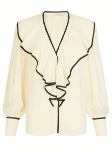 Détail de la blouse crème à col V avec volants bordés de noir et poignets boutonnés