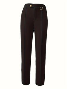 Detail of high-waist trousers with gold button and metal ring on irregular waistband