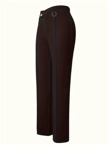Detail of high waisted trousers with vertical seams and gold metal ring decoration