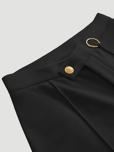 Detail of elegant black trousers featuring irregular waist design and golden metal buttons
