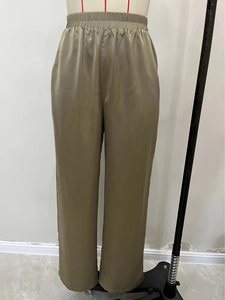 Detail of olive green satin wide-leg pants featuring a flexible pleated elastic waistband