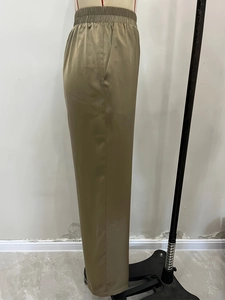 Detail of olive green satin wide-leg trousers showing smooth fabric and side pockets