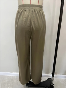 Detailed view of olive green wide leg satin trousers with a shiny silky fabric texture