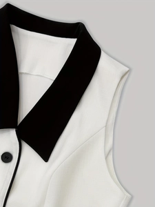 Close-up of black and white contrast trim vest with textured weave fabric and buttons