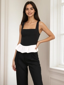 Dettaglio di un top peplum con scollo quadrato, corpetto nero e volant bianco svasato