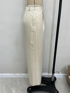 Detail shot of high-waisted wide-leg trousers in creamy white with premium draped fabric