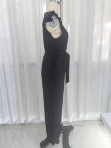 Zijaanzicht van een zwarte mouwloze jumpsuit met strikceintuur op een modepop