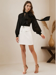 Detail of white A-line mini skirt featuring an elegant metallic buckle on the waistline
