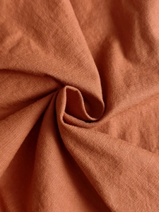 Vista macro del tessuto di lino marrone caramello che mostra la trama fine e il drappeggio