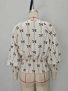 Détail de la taille smockée et des nœuds noirs sur cette blouse beige à manches amples