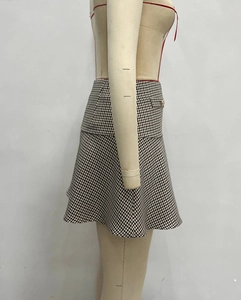 Detail of A-line plaid skirt featuring brown grid pattern and gold buckle accent