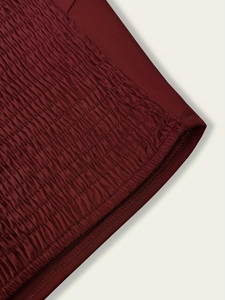 Détail d'un haut en satin bordeaux montrant les fronces et les coutures élastiques