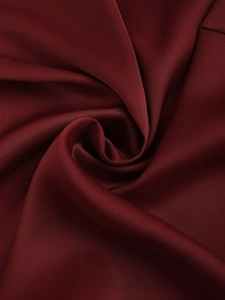 Vue macro d'un tissu satiné bordeaux élégant montrant une texture lisse et brillante