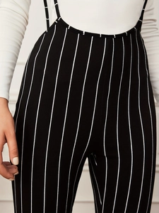 Macro shot of vertical black and white stripes on high-waisted wide-leg overalls pants
