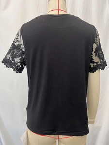 Detailed close-up of the elegant black lace hollowed sleeves and knit texture of the T-shirt