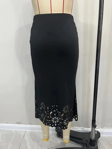 Détail d'une jupe midi noire taille haute en maille avec ourlet floral ajouré laser