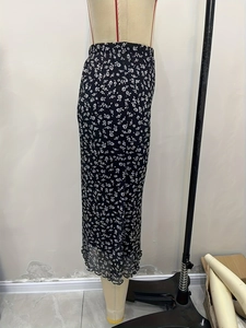 Detailed view of black high waist floral skirt with small white flowers and ruffle hem