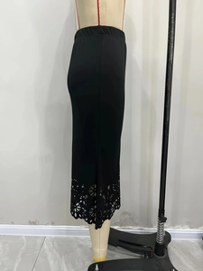 Détail d'une jupe noire en maille avec motifs floraux découpés au laser et taille élastique