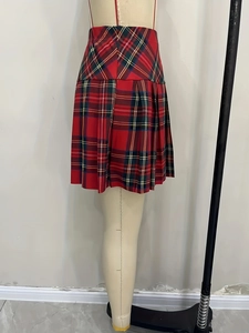 Detail of red and green plaid pleated skirt showing high waist cut and preppy style