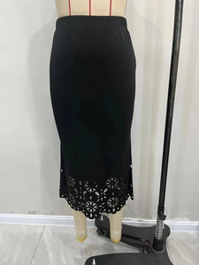 Détail de la jupe tricotée noire avec motifs floraux ajourés découpés au laser sur l'ourlet