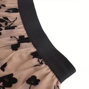 Close-up of beige mesh skirt with black flocked floral patterns and elastic waistband