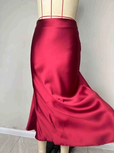 Detailed view of the red satin A-line maxi skirt showing glossy fabric texture and drape
