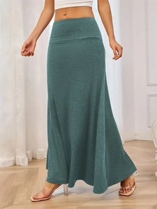 Detail showing the dark green knitted maxi skirt texture and elegant flowing hem design