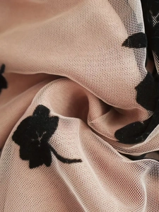 Nude mesh mini skirt featuring black flocked flower patterns and an A-line silhouette