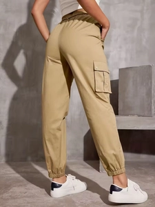 Khaki cargo pants with high waist and side flap pockets on a modern industrial background