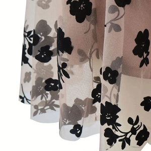 Close-up of black mesh fabric with floral flocking over a beige lining skirt