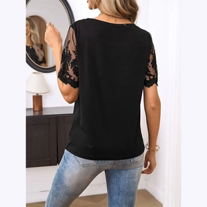 Detail of elegant black knit top with sheer mesh sleeves and floral embroidery