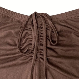 Detail of ruched adjustable drawstring and ribbed knit fabric on brown crop top