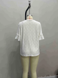 Detail of white top showing delicate eyelet embroidery and layered ruffle sleeve texture