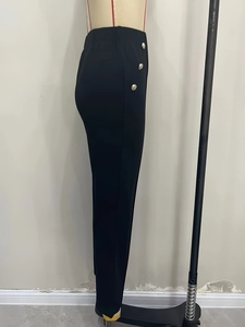 Détail du pantalon noir ajusté à taille haute avec trois boutons dorés décoratifs sur le côté