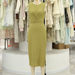 Detalle de un vestido sin mangas verde aguacate con textura arrugada y cintura cruzada