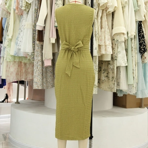 Detalle de la tela verde texturizada y lazo en la espalda de un vestido midi sin mangas