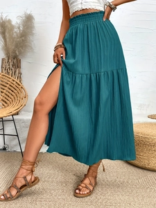 Detail of teal high-slit maxi skirt featuring pleated fabric and tiered ruffle hem