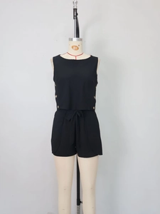 Detailed view of black sleeveless two-piece set featuring golden side buttons and waist tie