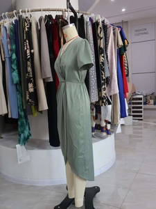 Detail of sage green satin wrap dress featuring elegant V-neck and asymmetric hemline