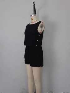 Detail of black sleeveless top with gold buttons and high waist wide leg shorts